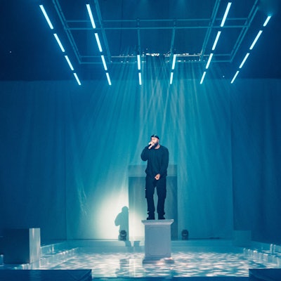 Rapper OG Keemo steht auf einer weißen Säule im Bühnenbild von "Die Troerinnen" im Depot 1 des Schauspiels Köln.