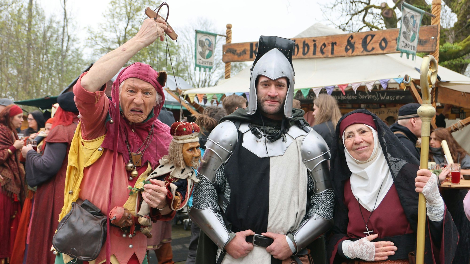Verkleidete Gaukler, Ritter und eine Nonne auf einem Mittelaltermarkt.