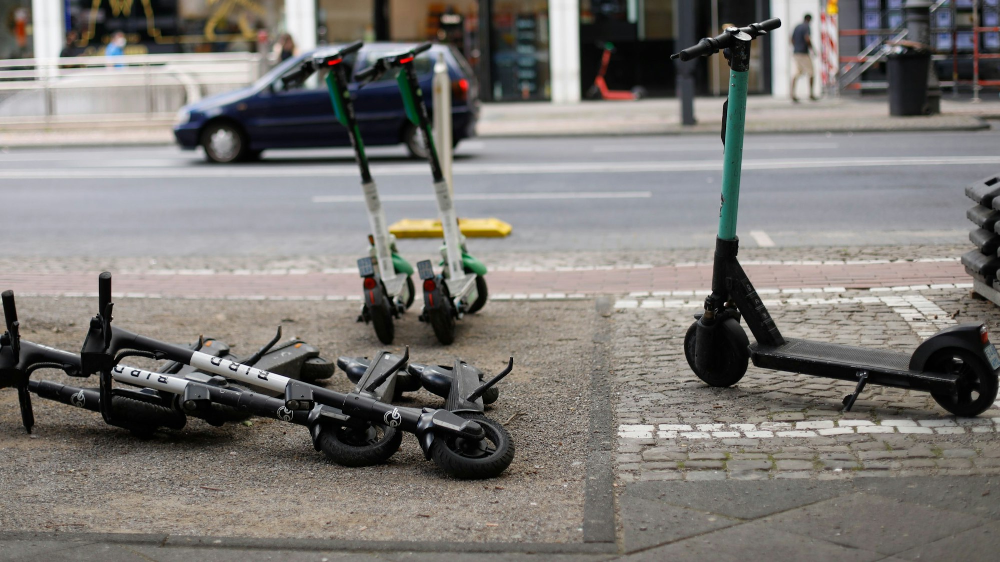 Abgestellte E-Scooter auf dem Gehweg in der Kölner Innenstadt versperren teilweise den Weg. Einige sind daneben ordnungsgemäß abgestellt worden. (Symbolbild)