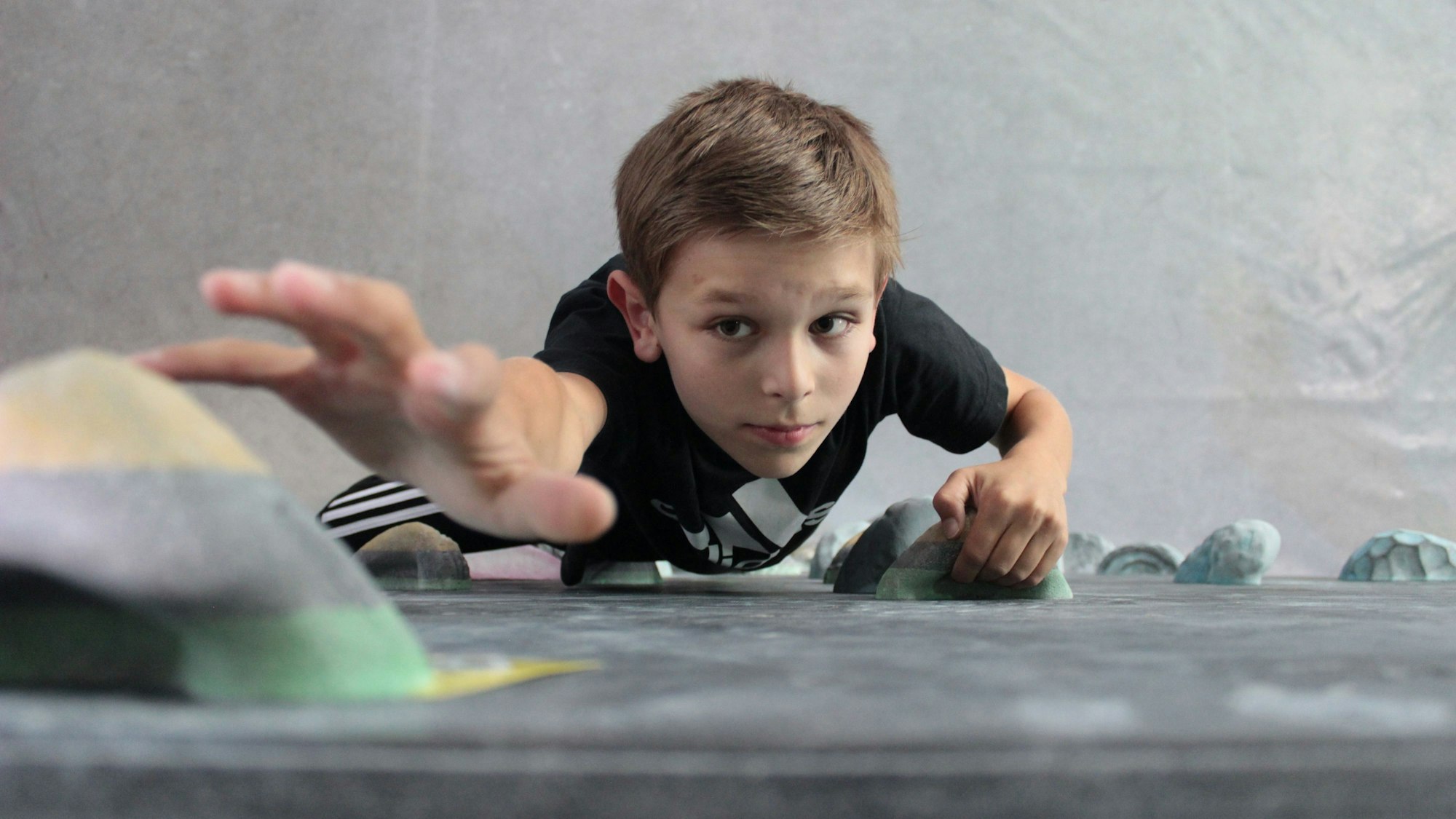 Ein Junge klettert in einer Boulderhalle.