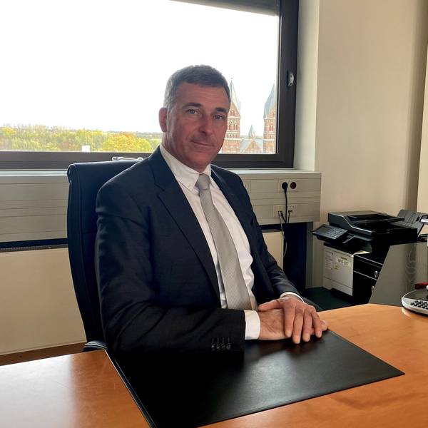 Ralph Manzke an seinem ersten Arbeitstag als Bürgermeister der Stadt Wesseling. Er sitzt mit übereinander gelegten Händen an seinem Schreibtisch und blickt in die Kamera.