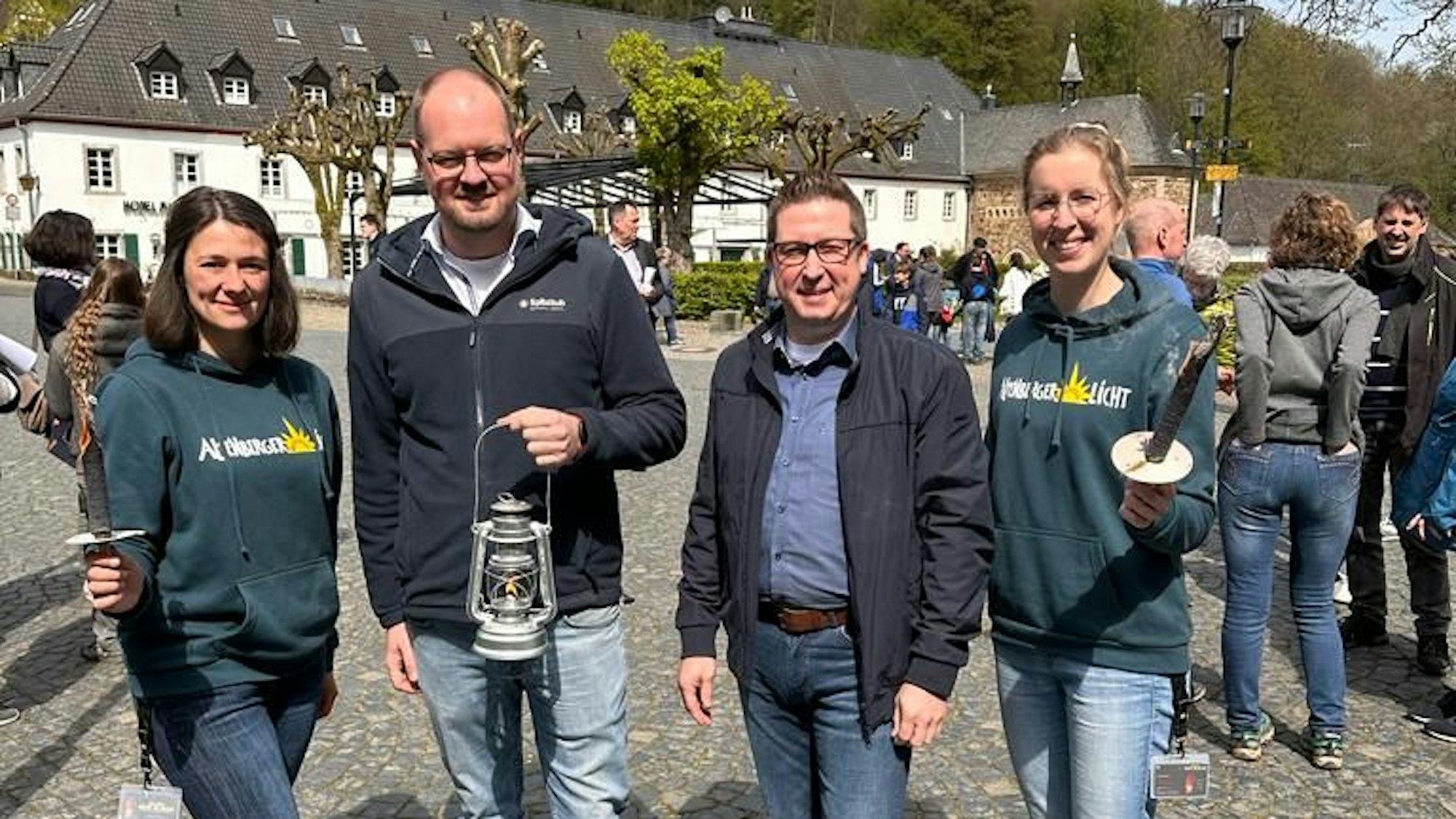 Vier Menschen stehen mit Fackeln und einer Laterne in der eine Flamme brennt auf dem Vorplatz des Altenberger Doms in der Gemeinde Odenthal.