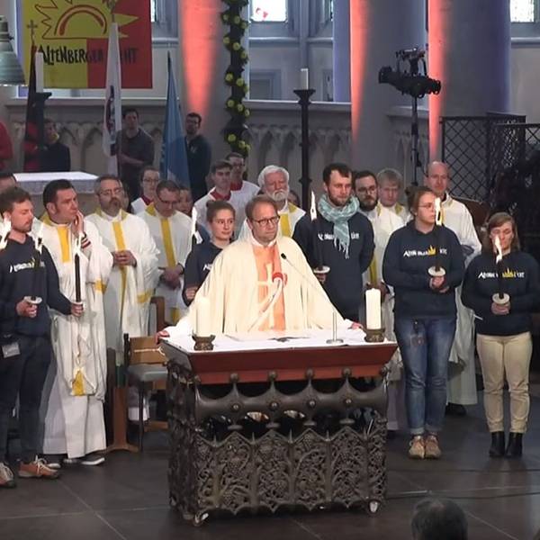 Diözesanjugendseelsorger Tobias Schwaderlapp steht am Altar des Altenberger Doms, während Frank Haag und Niklas Habers das Altenberger Licht für einen Hilfskonvoi ins ukrainische Butscha in Empfang nehmen.