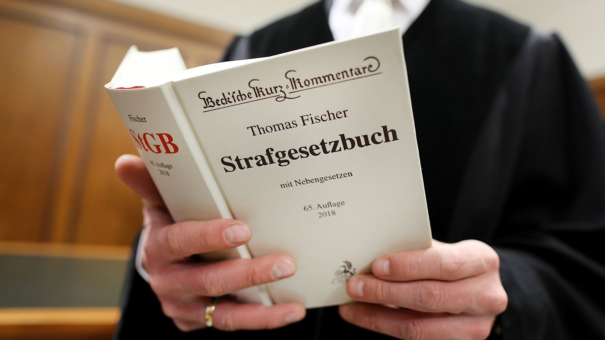 Zwei Hände halten das Strafgesetzbuch.