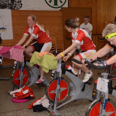 Nele Kauffmann (ganz links) und Vanessa Hayduk haben zwölf Stunden Radfahrt vor sich; Hedi Walisch (rechts) hatte Samstag und Sonntag je eine Stunde eingeplant. Alle Menschen auf dem Bild strampeln sitzend auf Indoor-Bikes.