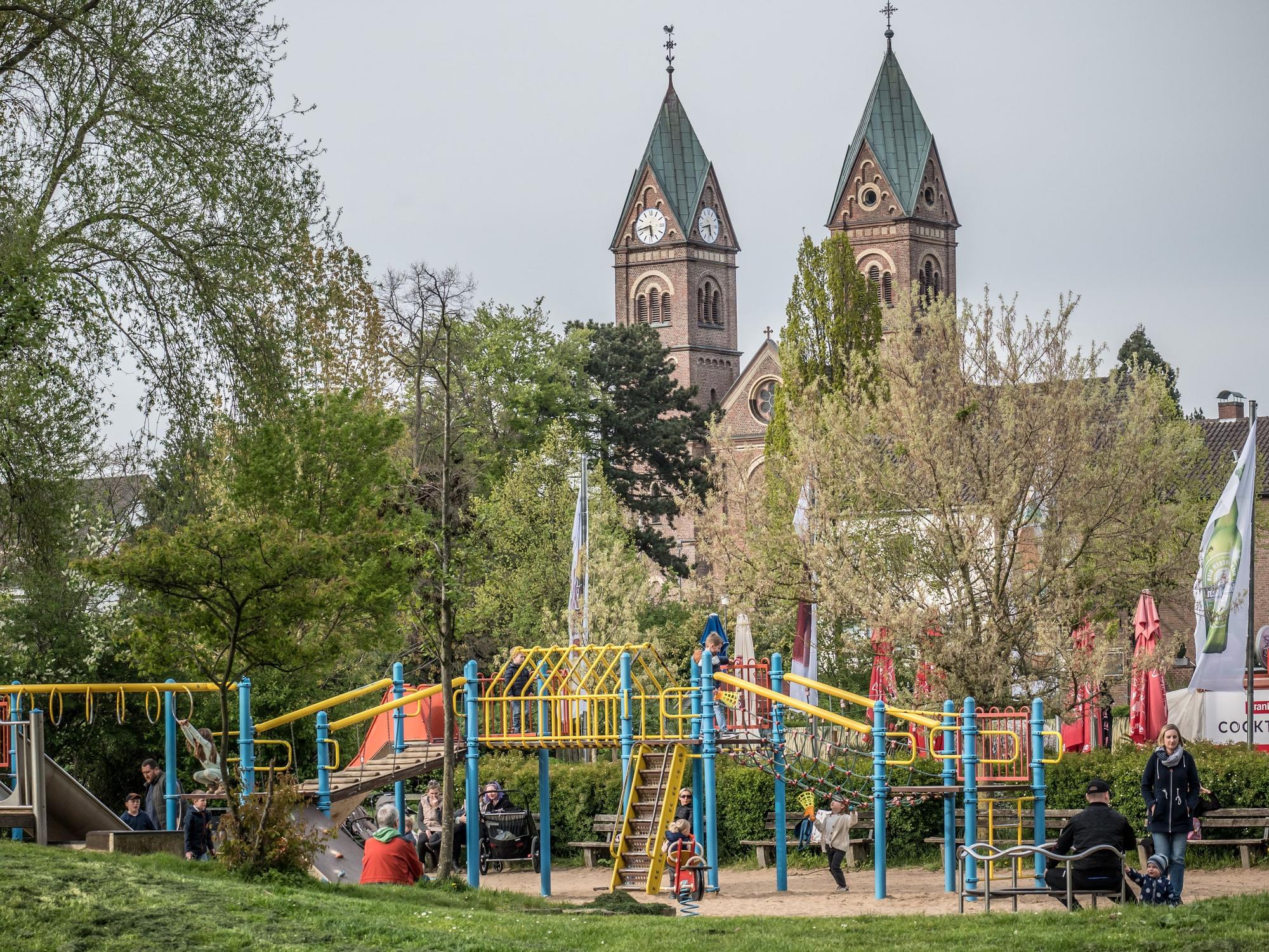Blick auf den Spielplatz mit Kirche dahinter.