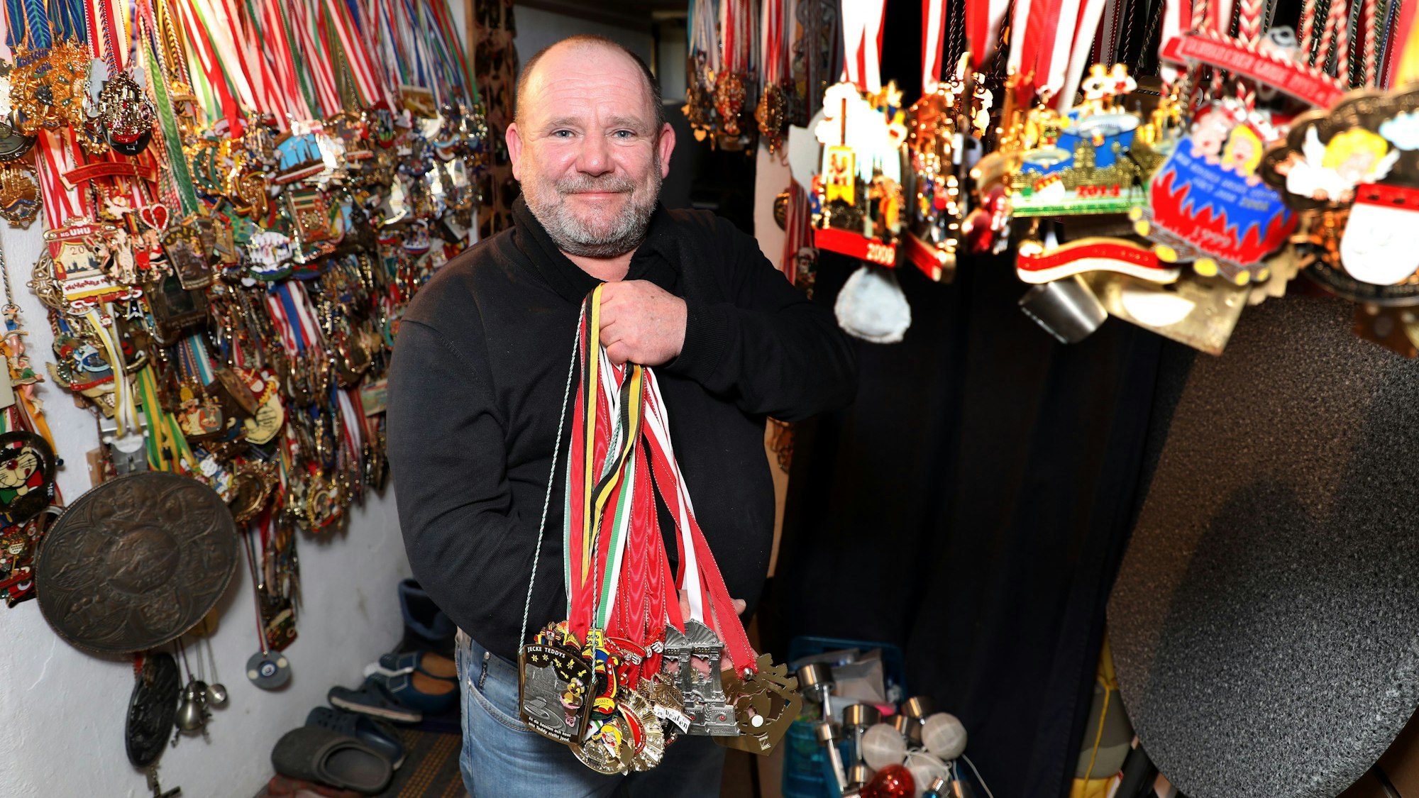 Der Karnevalist Frank Andes zeigt ein ganzes Bündel von Orden, an der Wand hängen mehrere Hundert weiterer Orden.