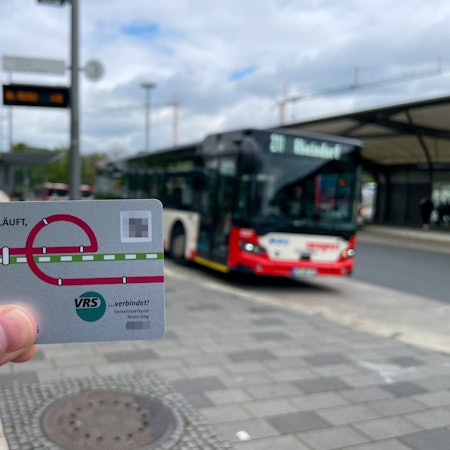 Im Vordergrund ist das Deutschlandticket zu sehen, im Hintergrund der Busbahnhof in Leverkusen-Mitte.