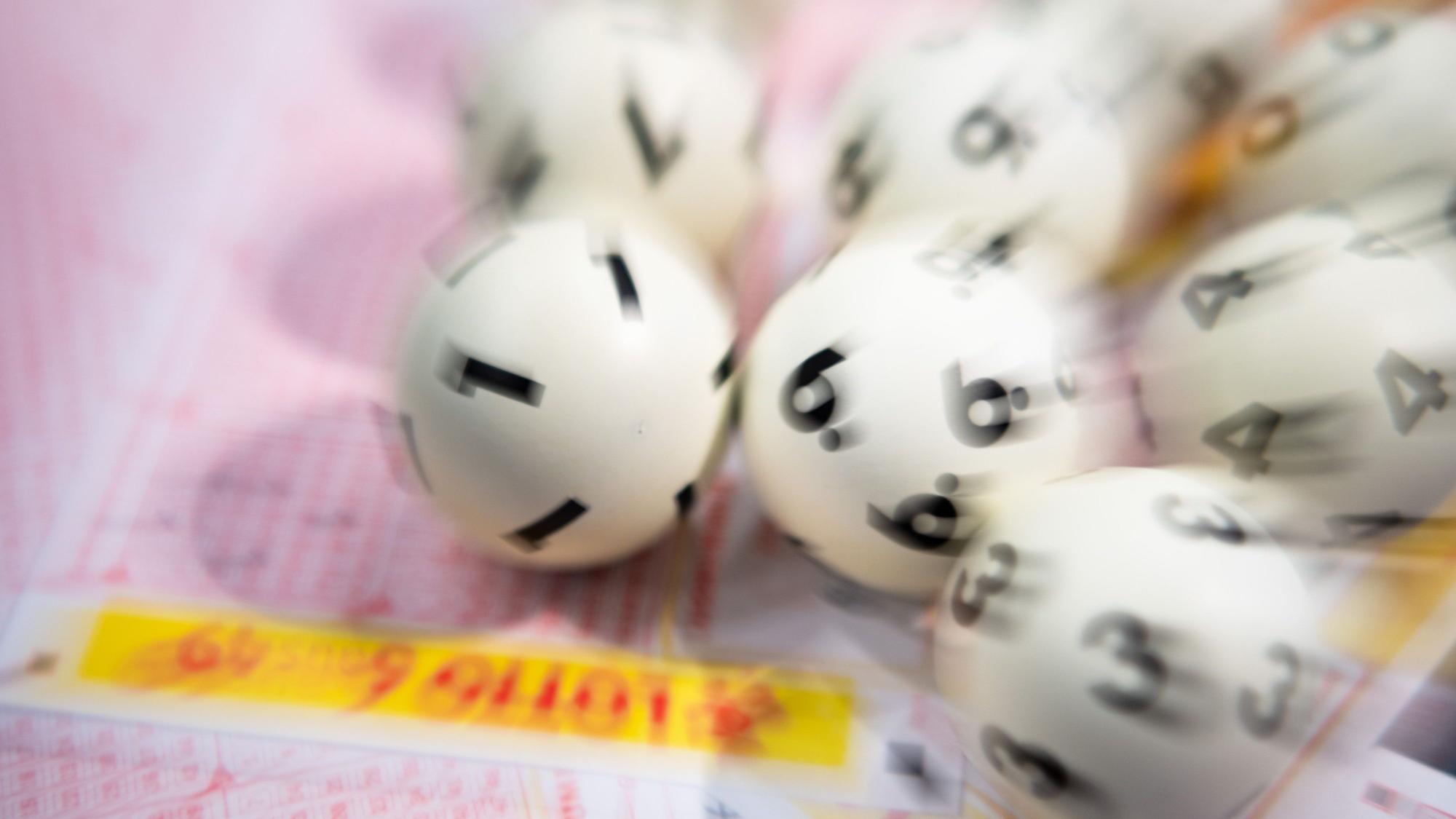 Lotto-Kugeln liegen auf einem Lottoschein (gestellte Szene, Aufnahme mit Zoomeffekt).