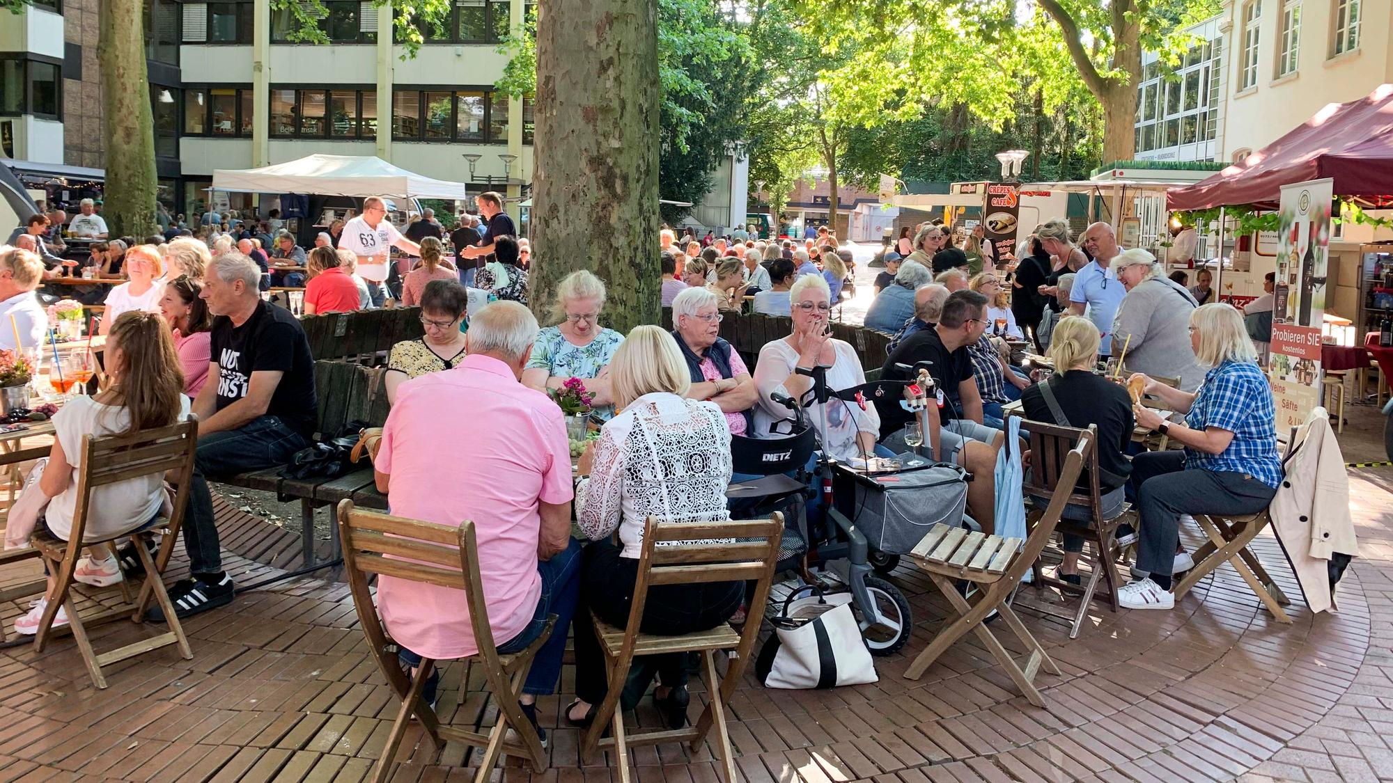 Das Bild zeigt Besucher des Feierabendmarktes, die an Tischen sitzen und essen.