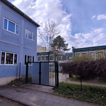 Ein blaues Container-Gebäude mit bunt beklebten Fenstern.