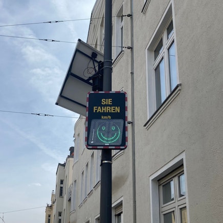 Eine digitale Geschwindigkeitsanzeige mit Smiley-Symbol.