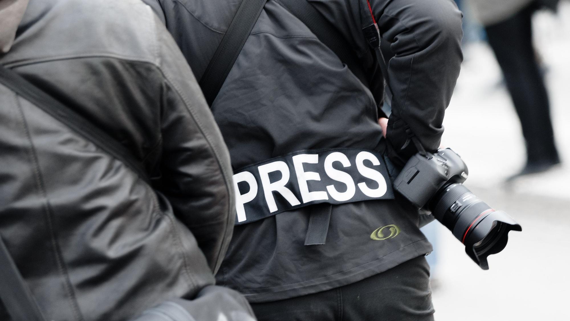 Ein Fotoreporter trägt auf einer Demonstration einen Aufnäher mit dem Text «PRESS» auf seiner Jacke, um sich gegenüber Polizei und Demonstranten als Journalist zu kennzeichnen.