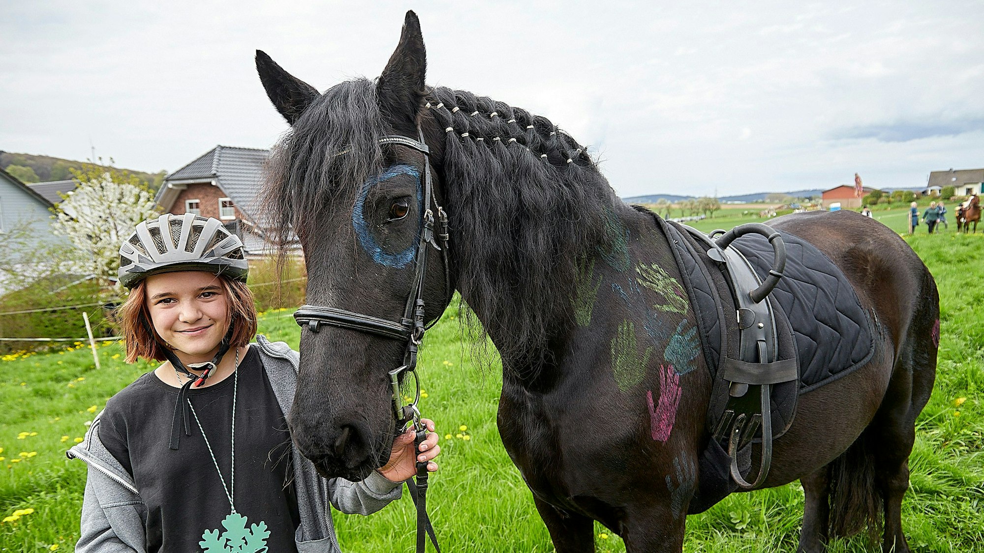 Es ist Julia Wilaszek mit ihrer bunt geschmückten Friesenstute Dusty zu sehen.