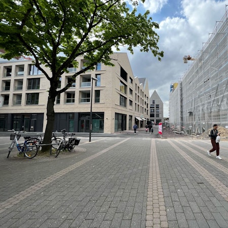 Die Porzer Innenstadt mit drei neuen Gebäuden und einer Fußgängerin.