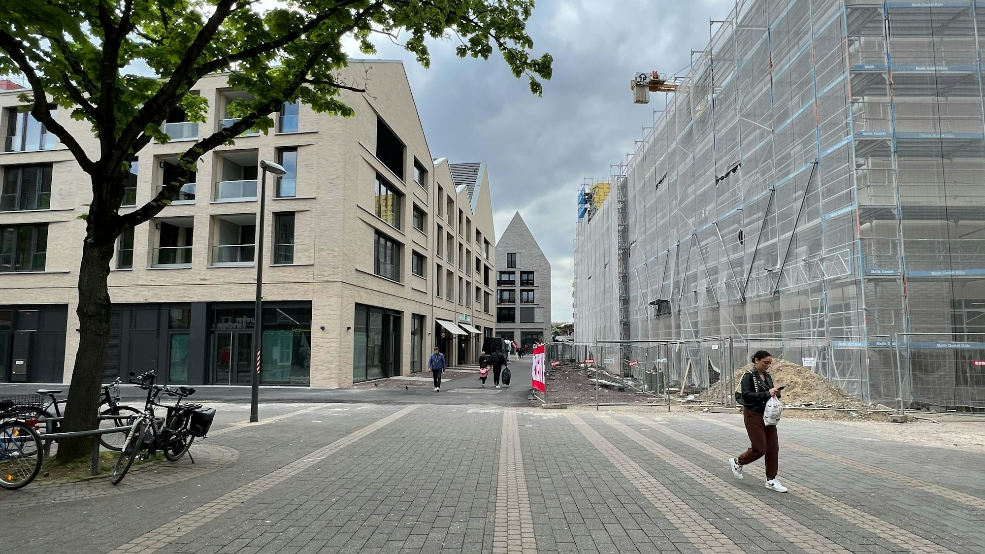 Die Porzer Innenstadt mit drei neuen Gebäuden und einer Fußgängerin.