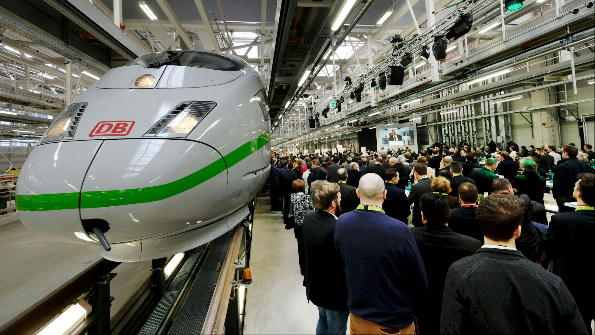 Eröffnung des ICE Werks in Köln-Nippes: Ein neuer ICE-Typ wird präsentiert, viel Publikum ist in einer Werkhalle zu sehen.