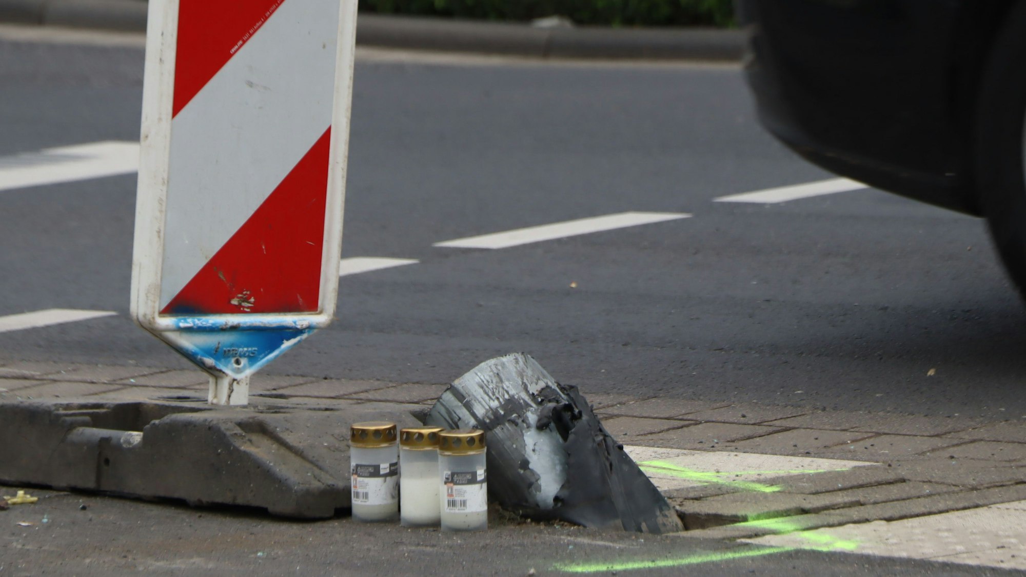 Das Foto zeigt die Unfallstelle in Hürth. An den abgesägten Ampelmast sind Kerzen aufgestellt worden.