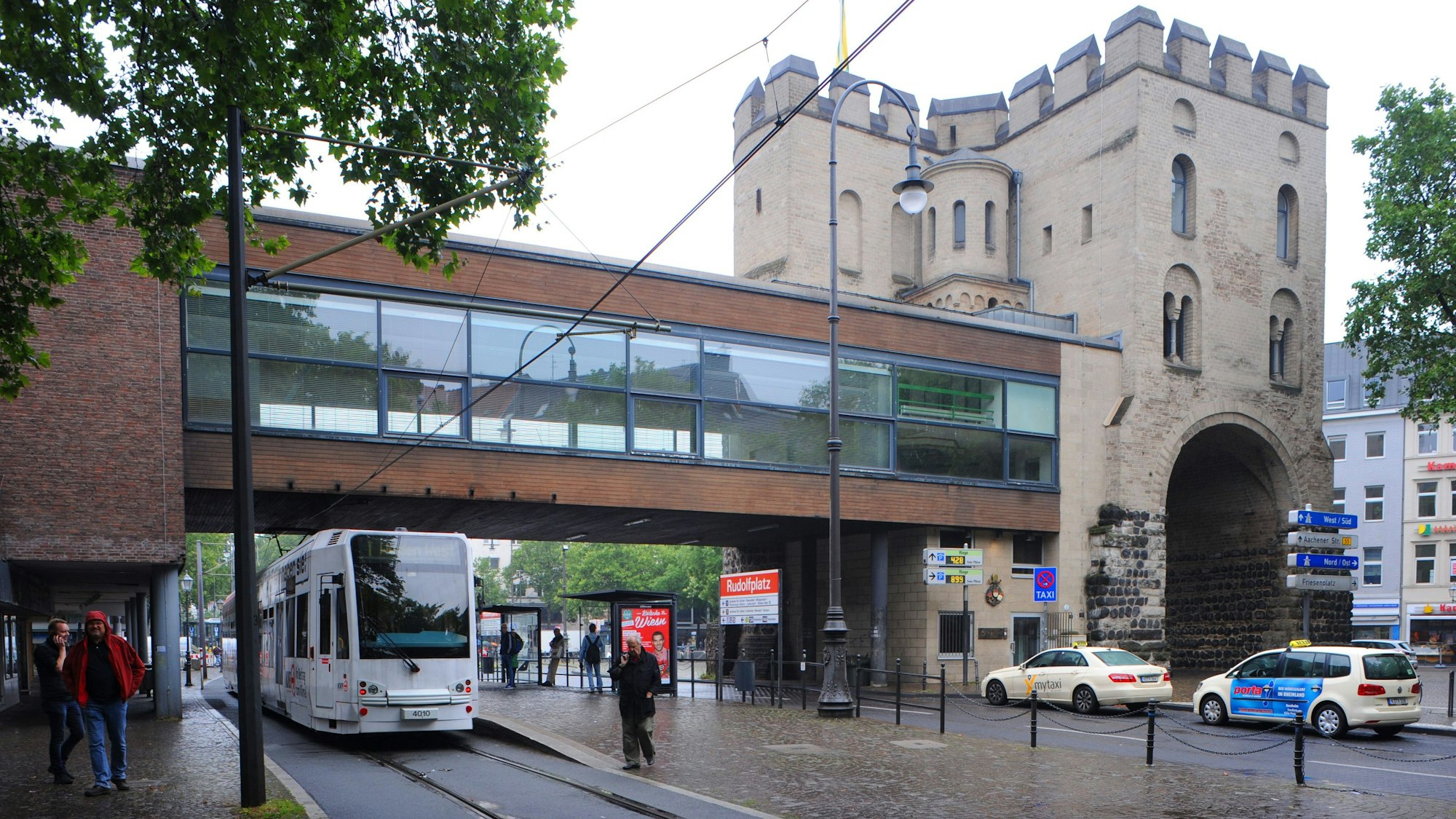Das Bild zeigt die frühere Brücke über die Hahnenstraße, darunter fahren Autos und eine Bahn.