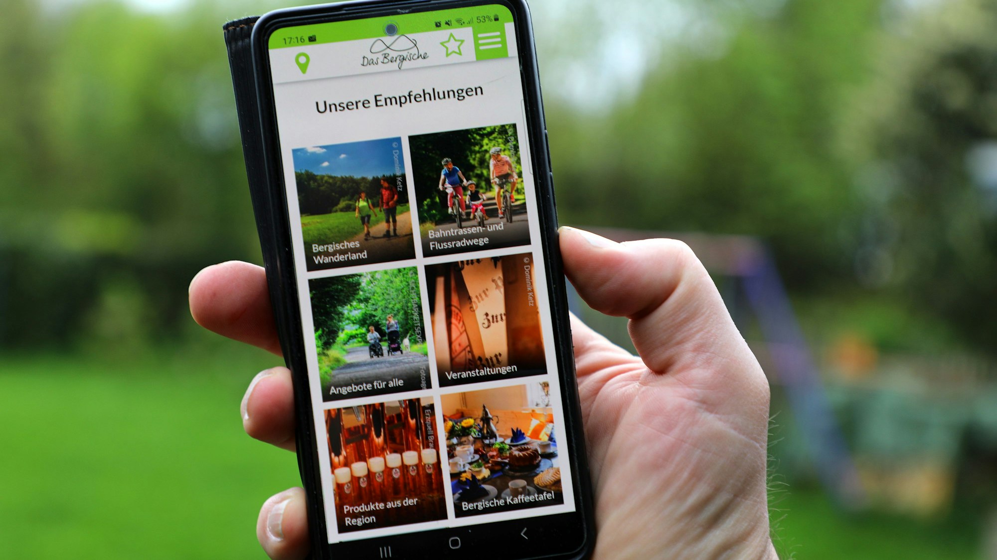 Die Freizeit-App von „Das Bergische“ wird auf einem Smartphone in einer Menschenhand dargestellt.