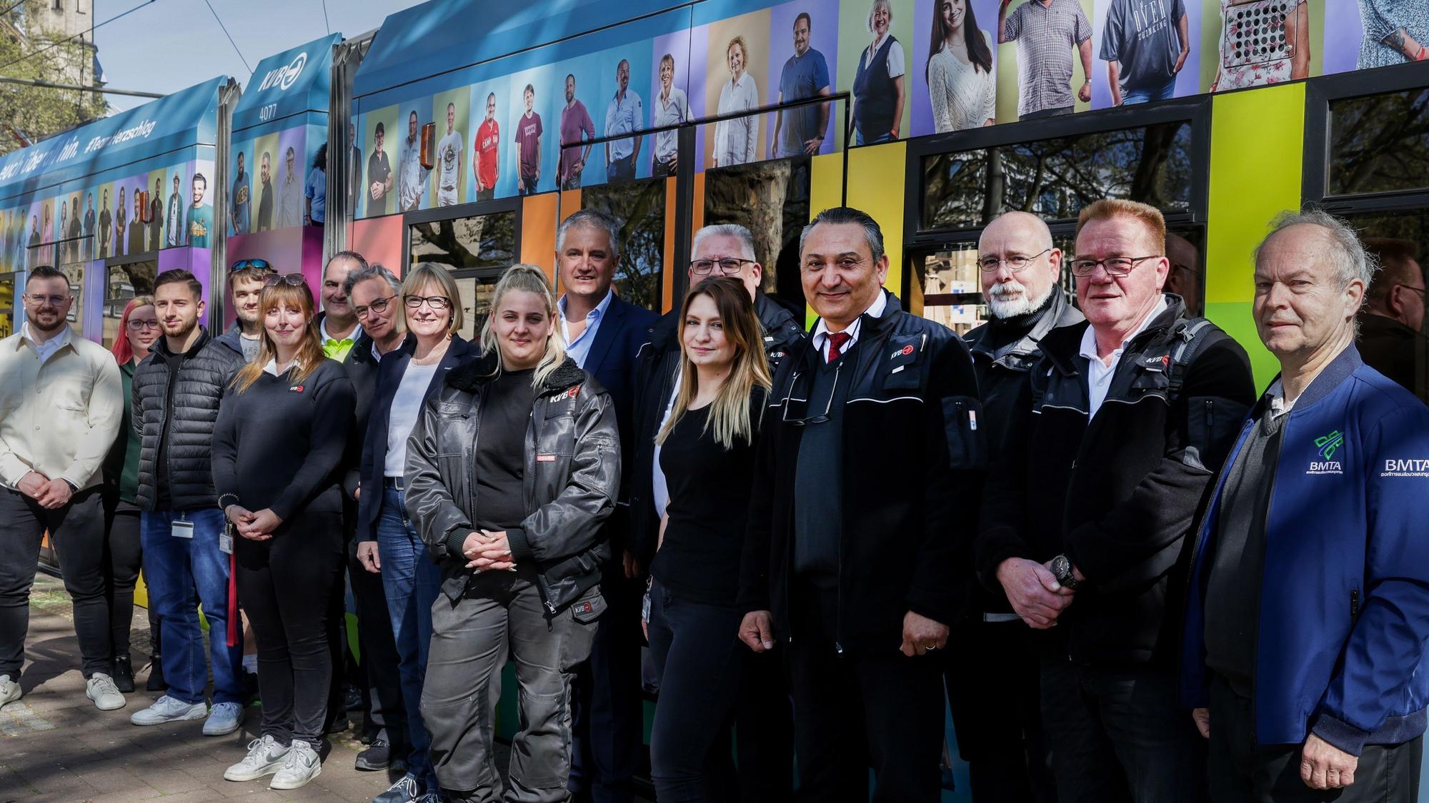 Menschen, die vor einer bunten Straßenbahn stehen
