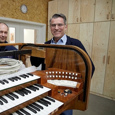 Zwei Männer stehen an einer historischen Orgel, in die nun digitale Technik eingebaut wird.