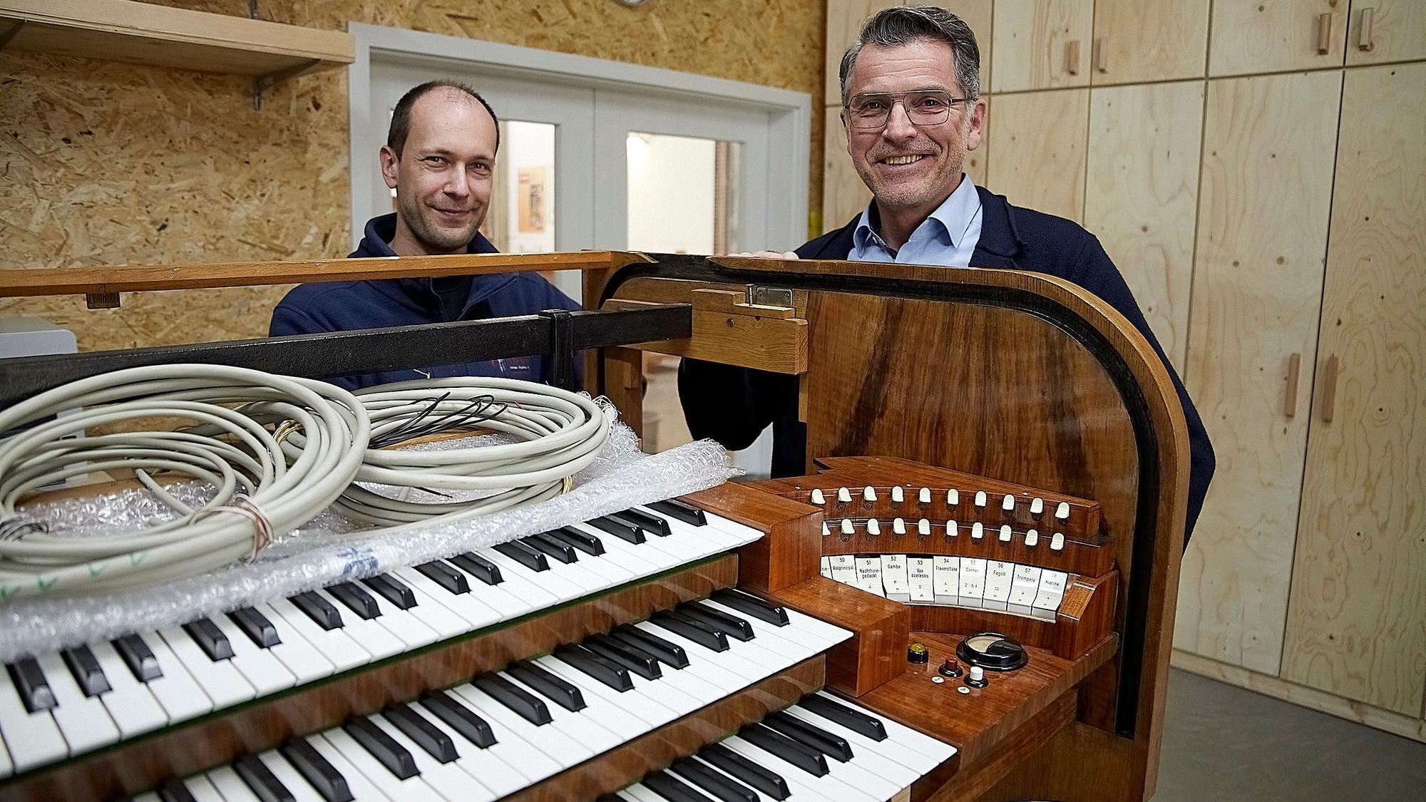 Zwei Männer stehen an einer historischen Orgel, in die nun digitale Technik eingebaut wird.