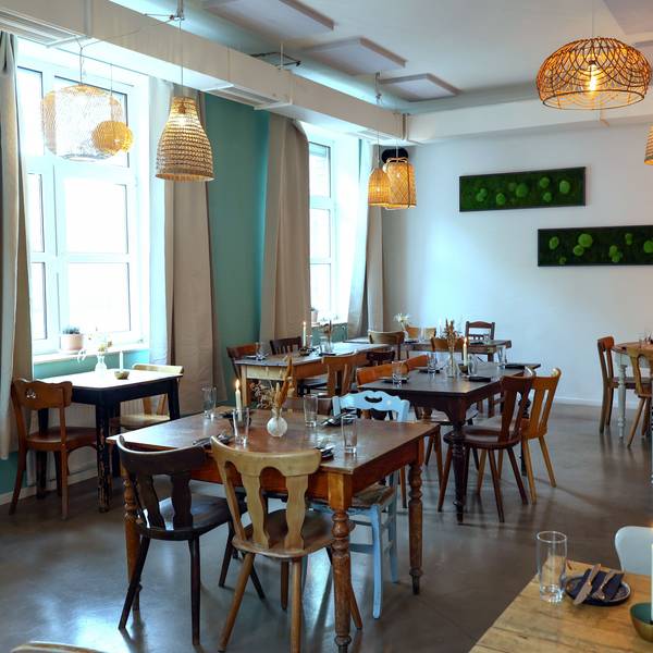 Holztische und -stühle mit Blumen und Kerzen in einem Restaurant