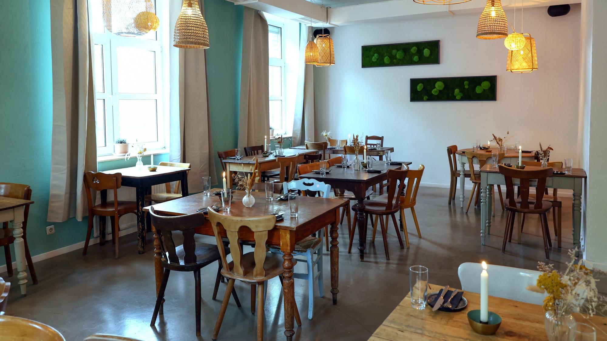 Holztische und -stühle mit Blumen und Kerzen in einem Restaurant