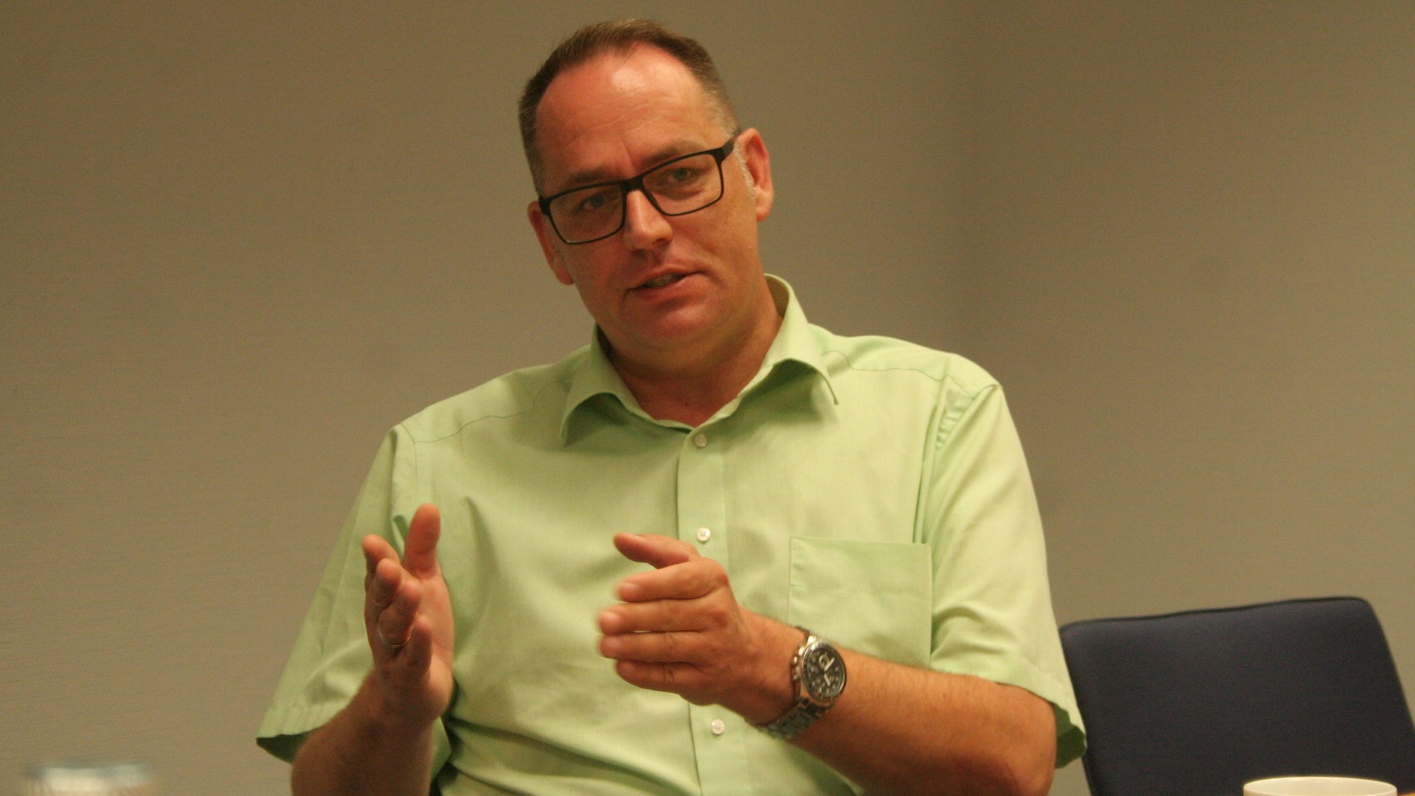 Andreas Lipp (SPD) trägt eine Brille, eine Armbanduhr und ein grünes Hemd und gestikuliert.