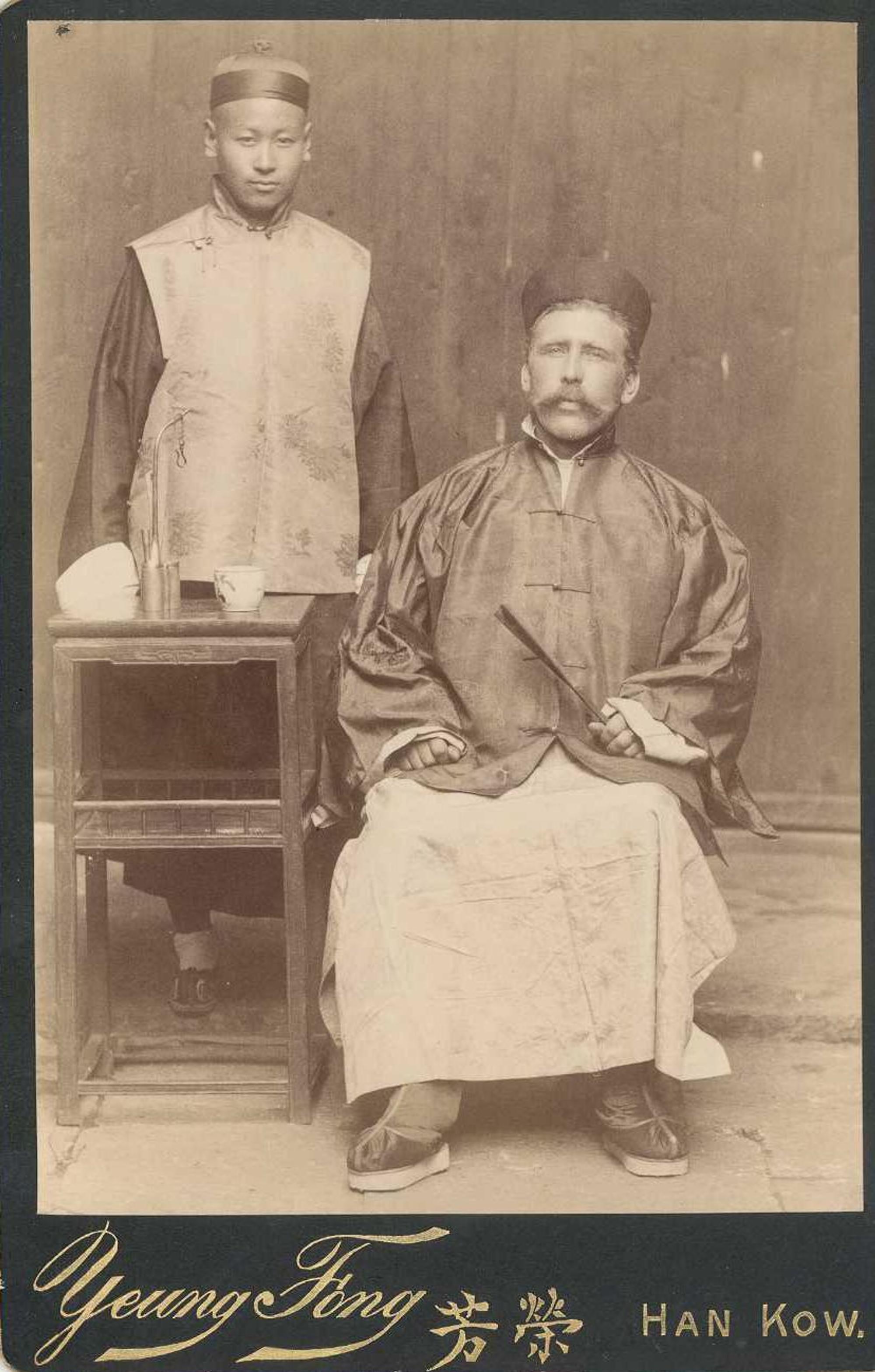 Heinrich Hildebrand und ein unbekannter Assistent posieren in chinesischer Kleidung vor der Kamera.