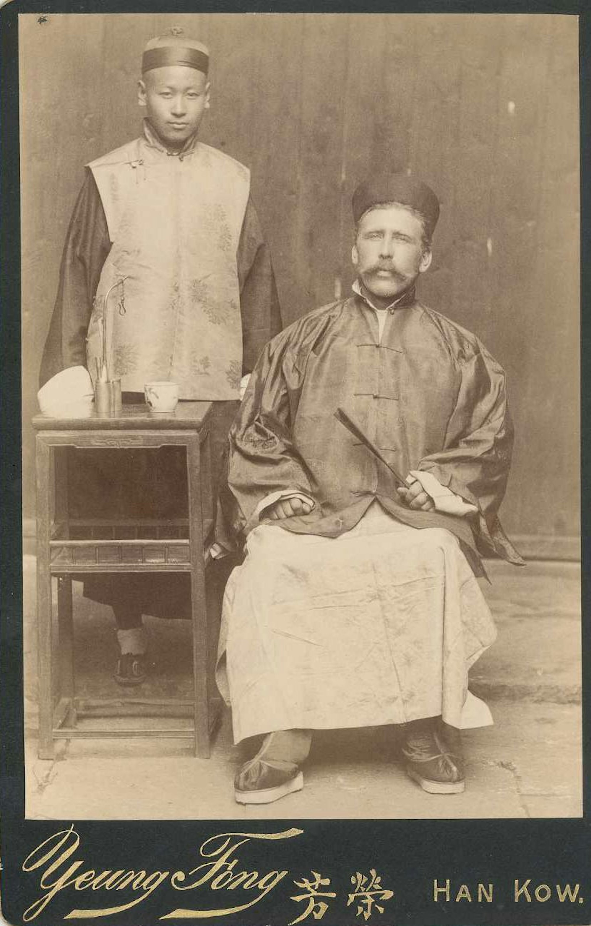 Heinrich Hildebrand und ein unbekannter Assistent posieren in chinesischer Kleidung vor der Kamera.