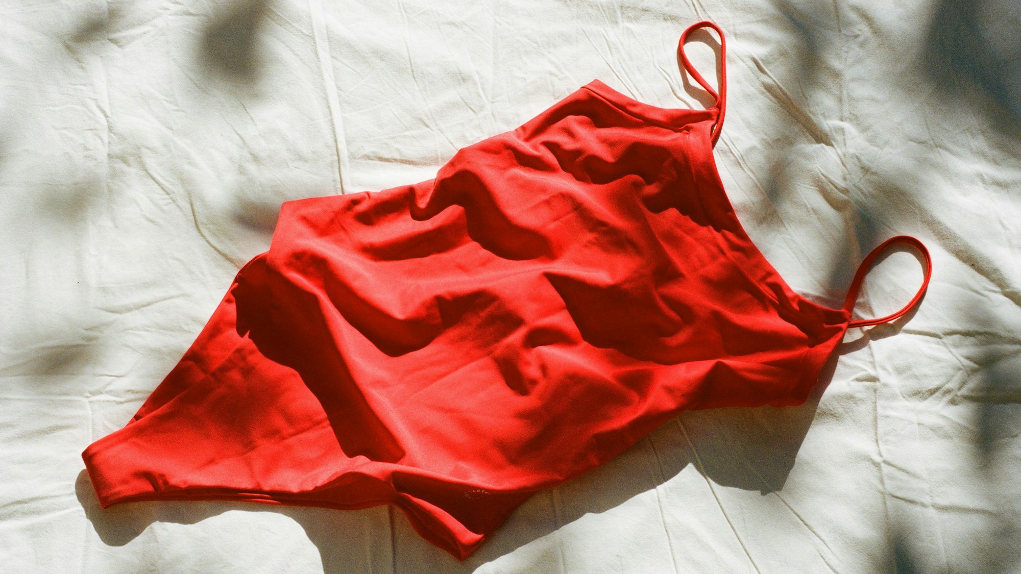 Ein nachhaltiger Badeanzug aus alten Fischernetzen von dem Label „Copenhagen Cartel" liegt auf einem weißen Tuch.