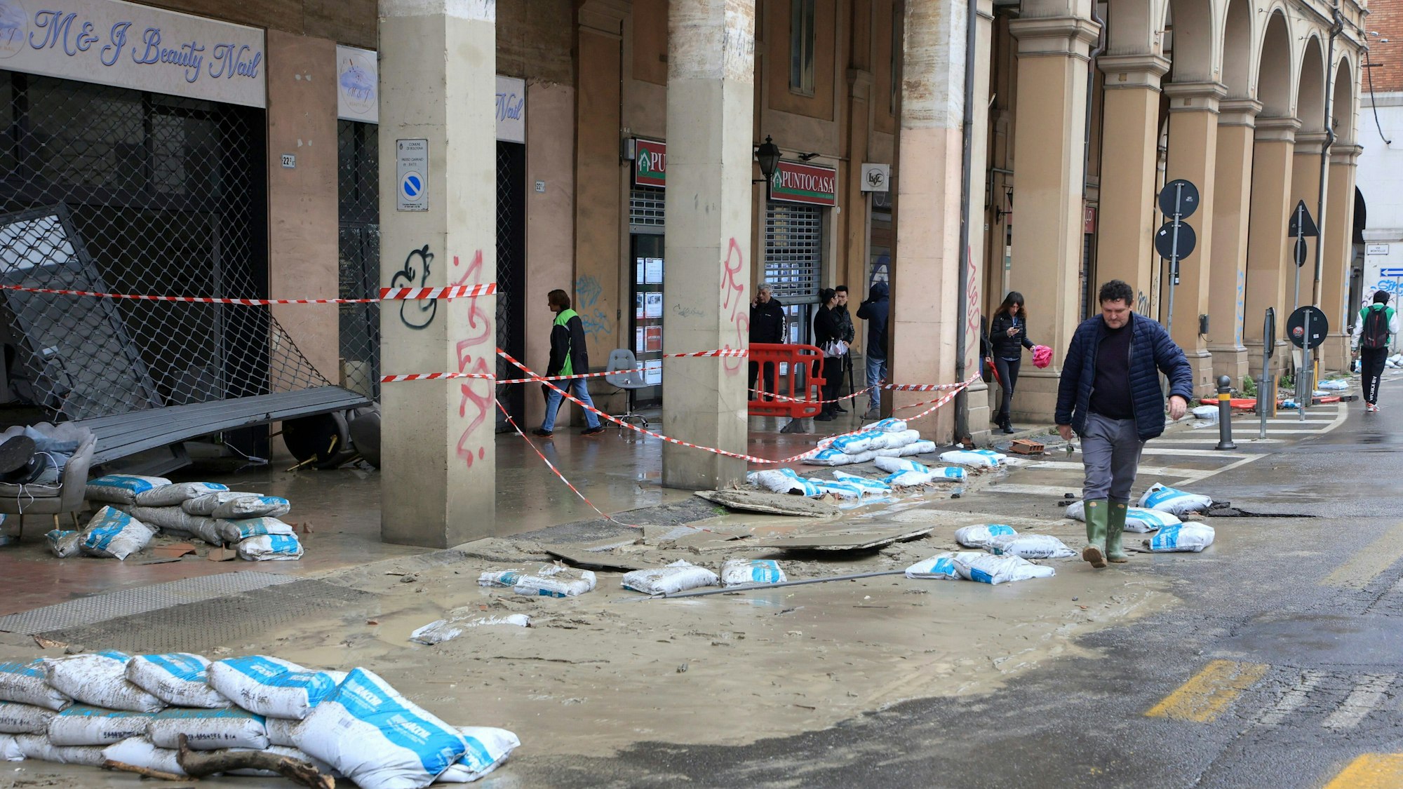 Bologna in Italien: Ein Mann geht in Gummistiefel vorbei an Schäden, die durch ein Hochwasser ausgelöst wurden. Nach heftigen Regenfällen ist es in der italienischen Region Emilia-Romagna zu teils dramatischen Überschwemmungen gekommen