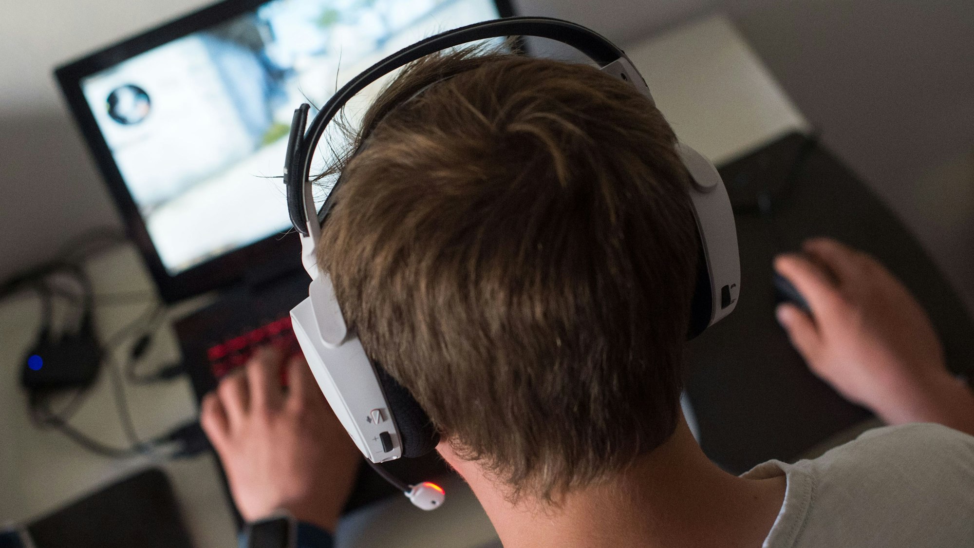 Ein junger Mann sitzt an einem Schreibtisch und spielt ein PC-Spiel.