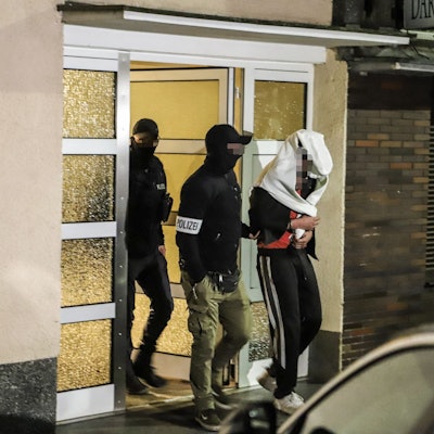 Die Polizei führt am 3. Mai 2023 eine festgenommene Person aus einem Wohnhaus in Hagen.