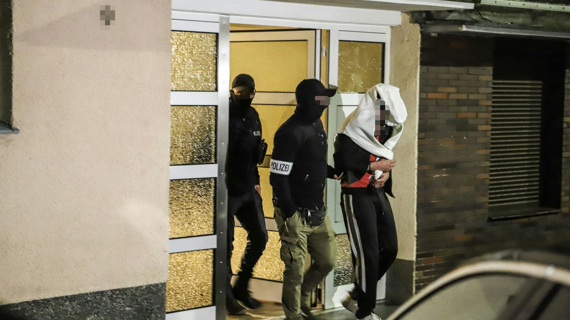 Die Polizei führt am 3. Mai 2023 eine festgenommene Person aus einem Wohnhaus in Hagen.