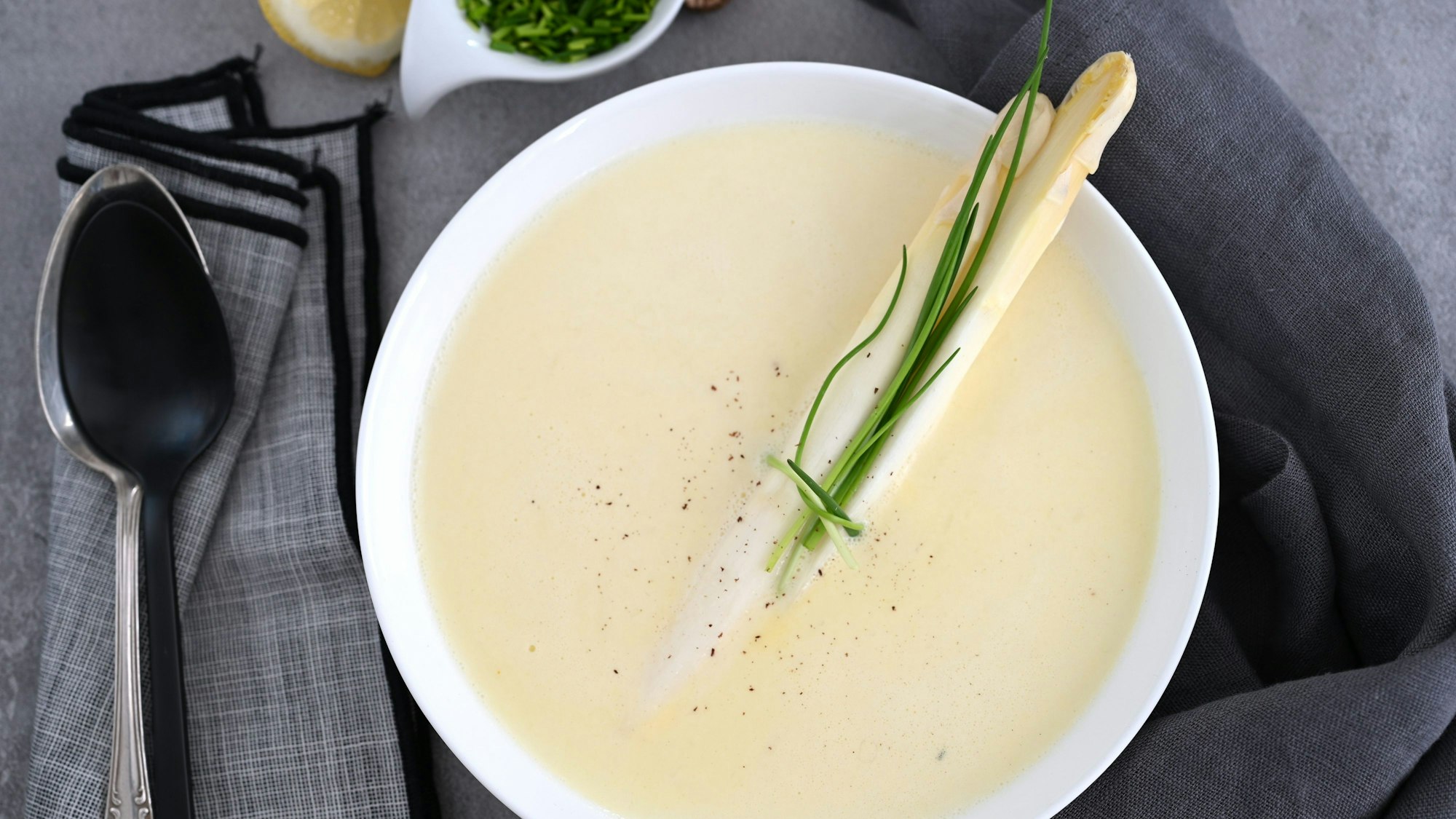 Eine Sparrgelcremesuppe steht auf einem schlicht gedeckten Tisch.
