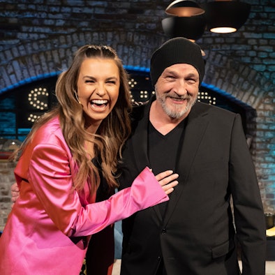 Torsten Sträter und Laura Wontorra vor der Kulisse seiner Sendung, beide lachen in die Kamera.