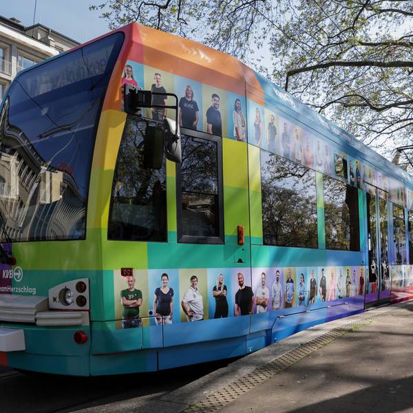 Stehende Straßenbahn, die mit bunten Kacheln und Fotos von KVB-Mitarbeitenden beklebt ist