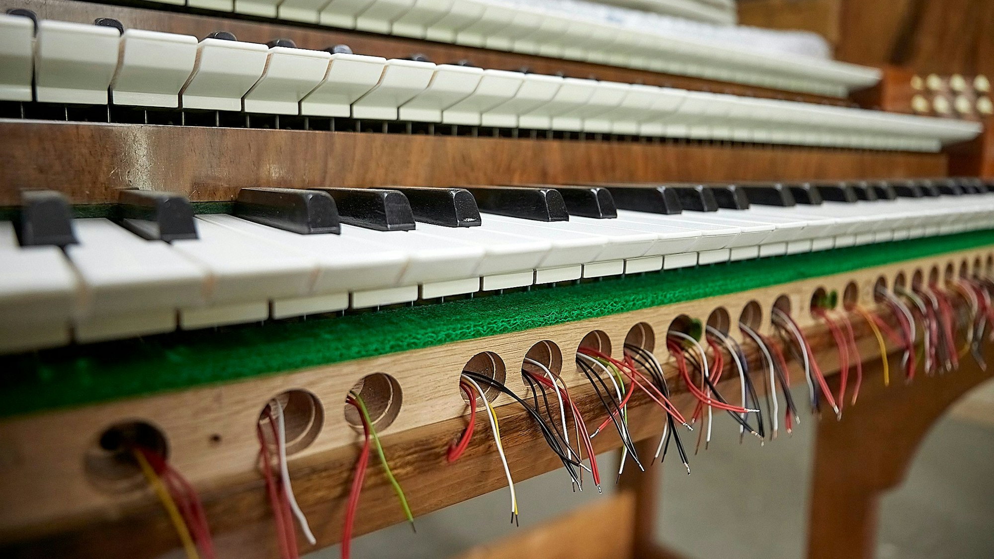 Von Kabeln durchzogen ist das Innere eines Orgel-Spieltischs.