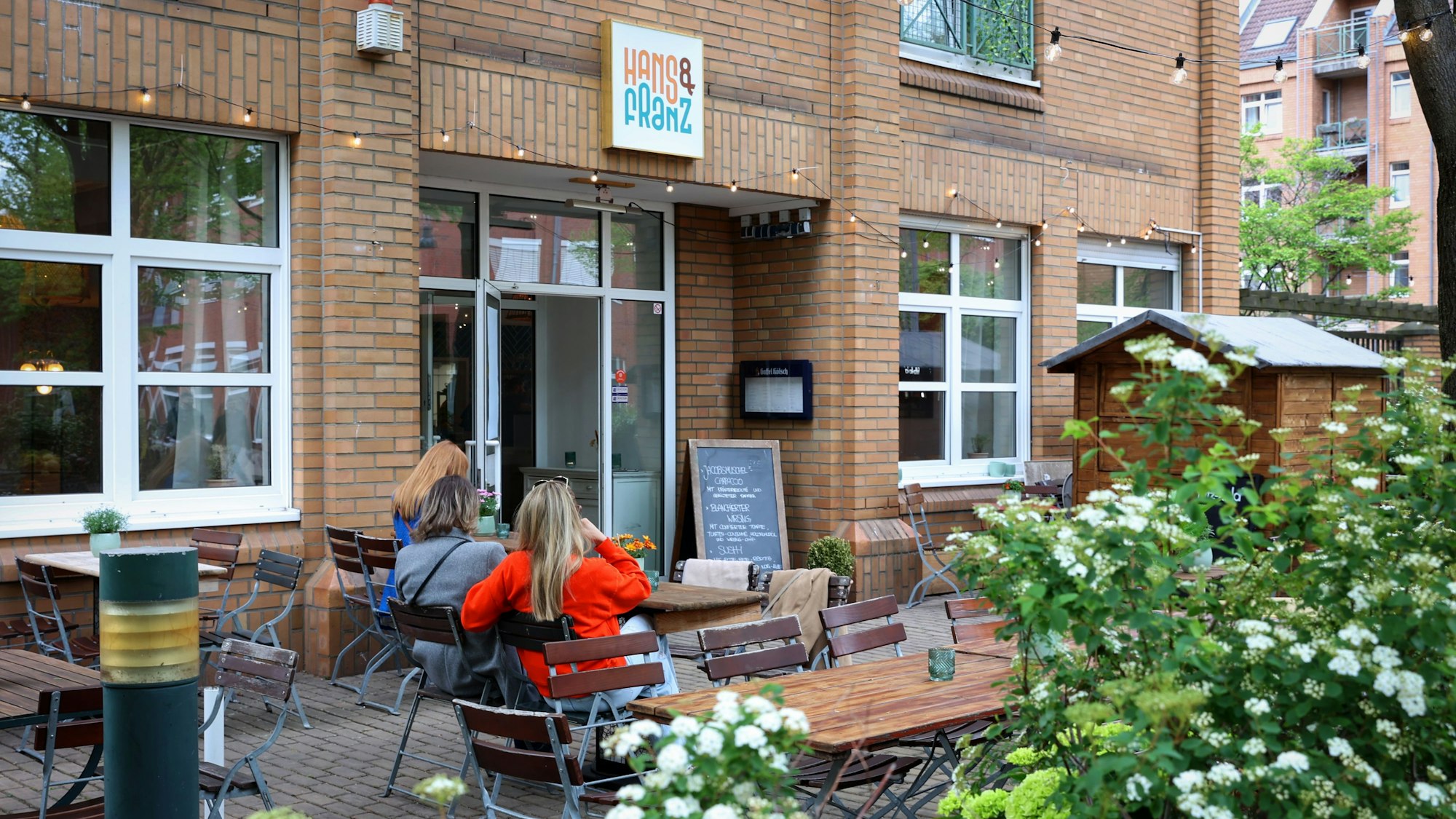 drei Frauen sitzen auf einer Terrasse vor einem Restaurant