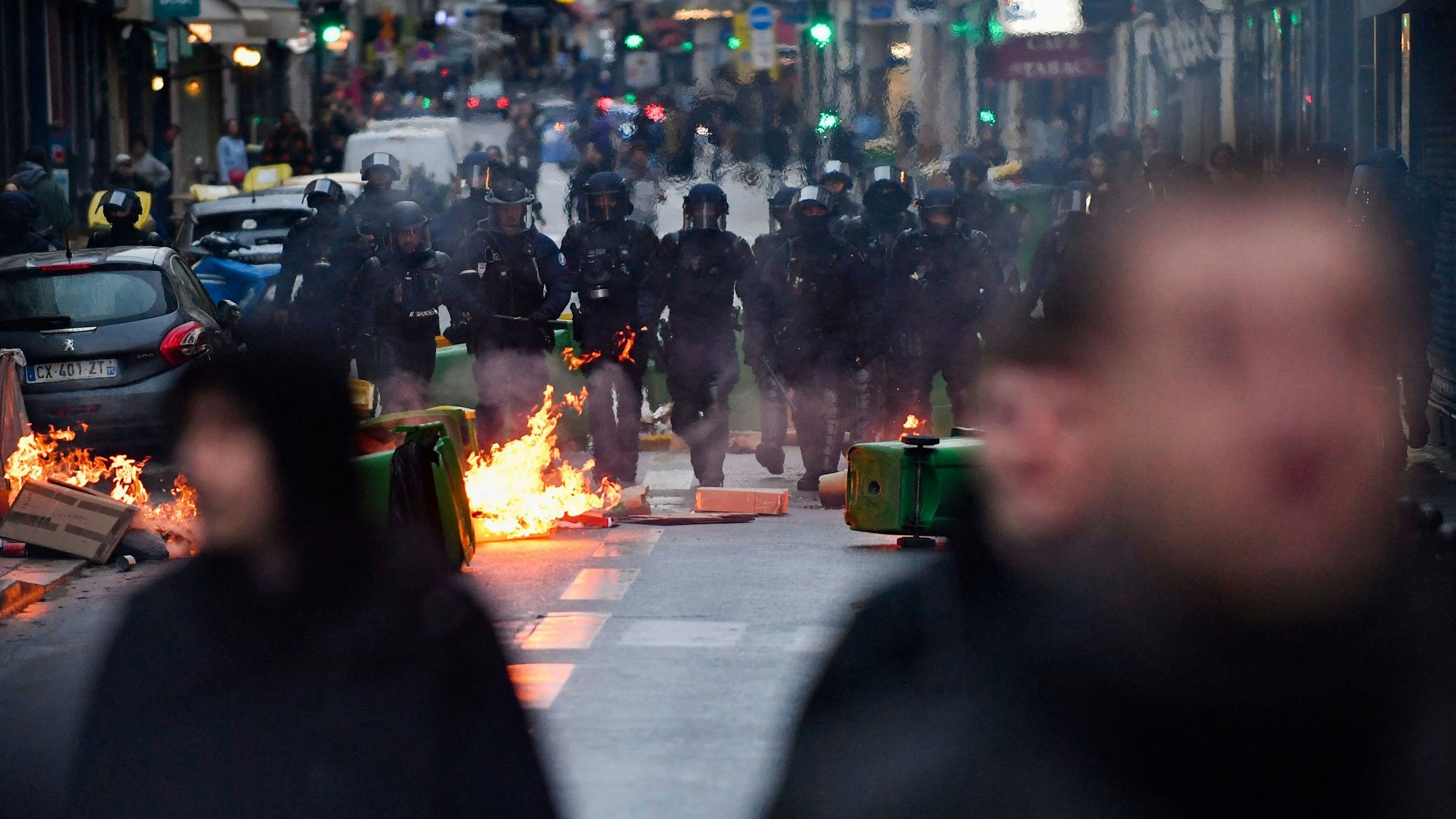 14.04.2023, Frankreich, Paris: Polizisten gehen während einer Demonstration an einem Feuer vorbei, nachdem das französische Verfassungsgericht die wichtigsten Elemente der umstrittenen Rentenreform gebilligt hat.