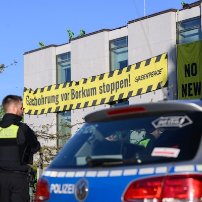 Polizisten beobachten, wie Aktivisten der Umweltschutzorganisation Greenpeace am frühen Morgen Banner an der Fassade des niedersächsischen Landtages befestigen. Greenpeace protestiert gegen eine Gasbohrung vor der Nordseeinsel Borkum.