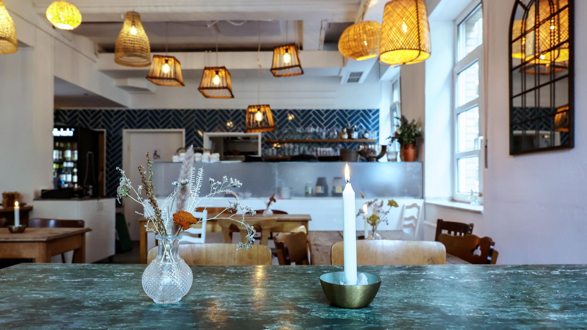 ein kleiner Blumenstrauß und eine brennende Kerzen stehen auf einem Tisch in einem Restaurant