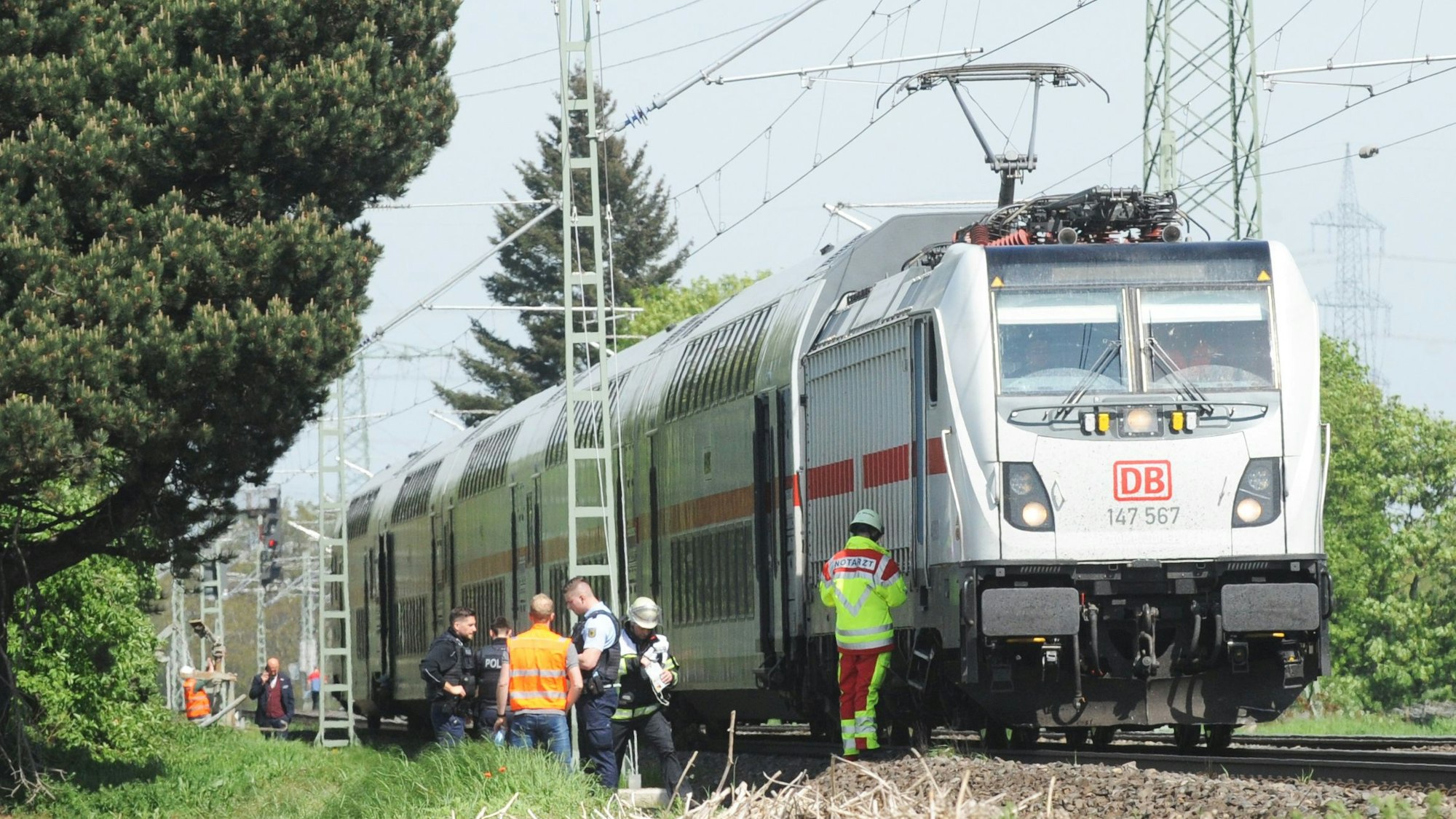 Das Bild zeigt einen Personenzug und mehrere Einsatzkräfte an der Unglücksstelle.
