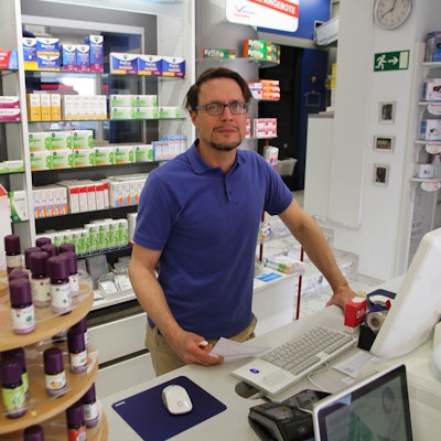 Es ist der Apotheker Marc Remmel zu sehen, wie er hinter seinem Tresen steht.