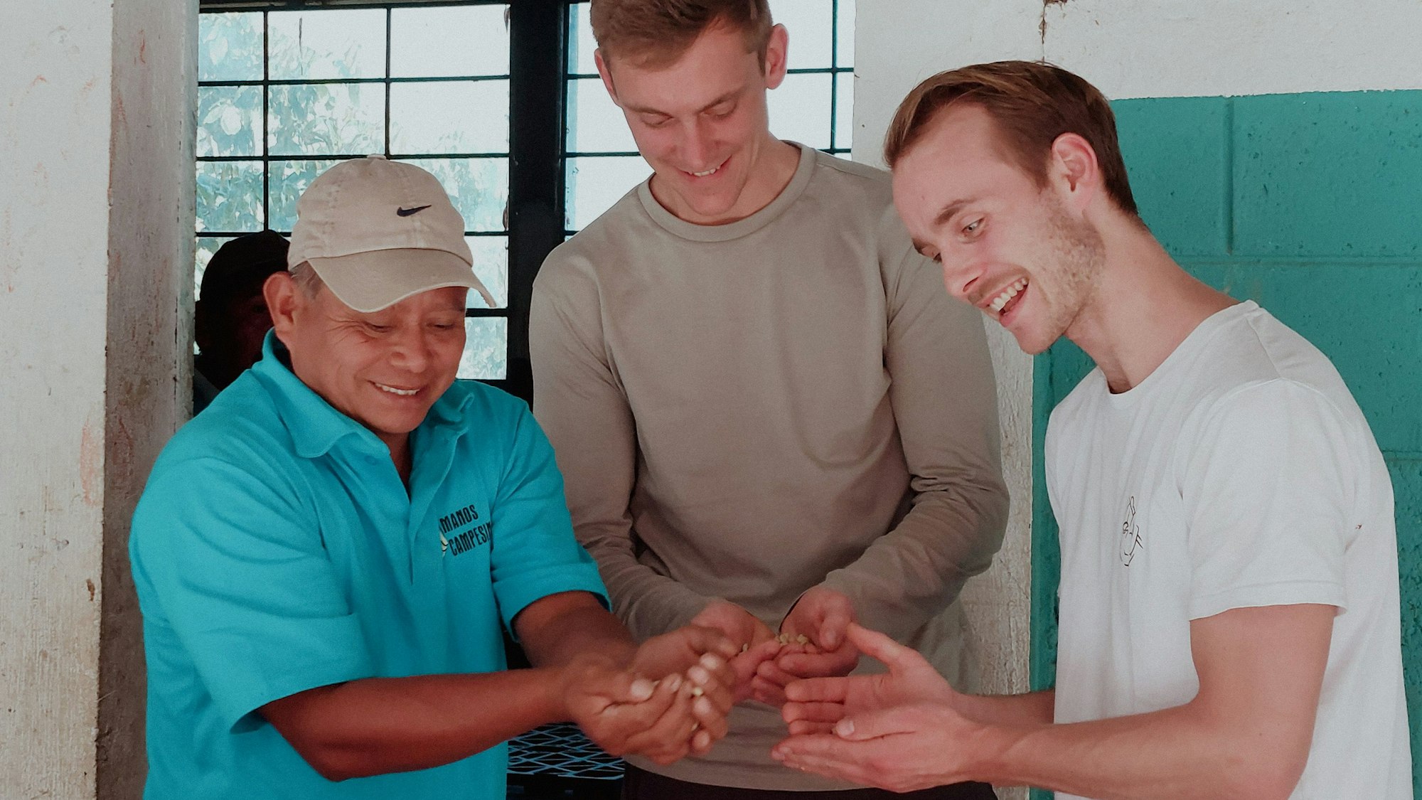 Oswaldo Chávez Gabriel (l.), Präsident der Kooperative Adiba, zeigt Frederik Baumann und Tilman Böing (r.) von Zwoo Kaffeeröster die Ernte der Kaffeebauern.