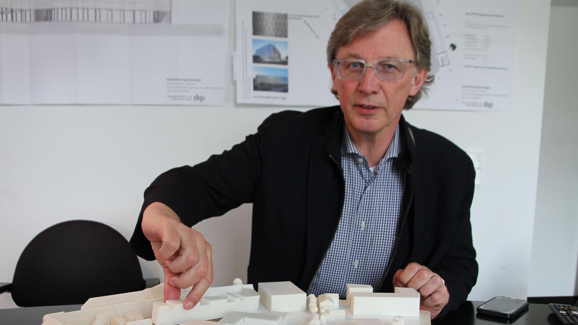 André Kuchheuser, der Vorstand der Siegburger Stadtbetriebe, sitzt in einem Büro vor einem Architektur-Modell.
