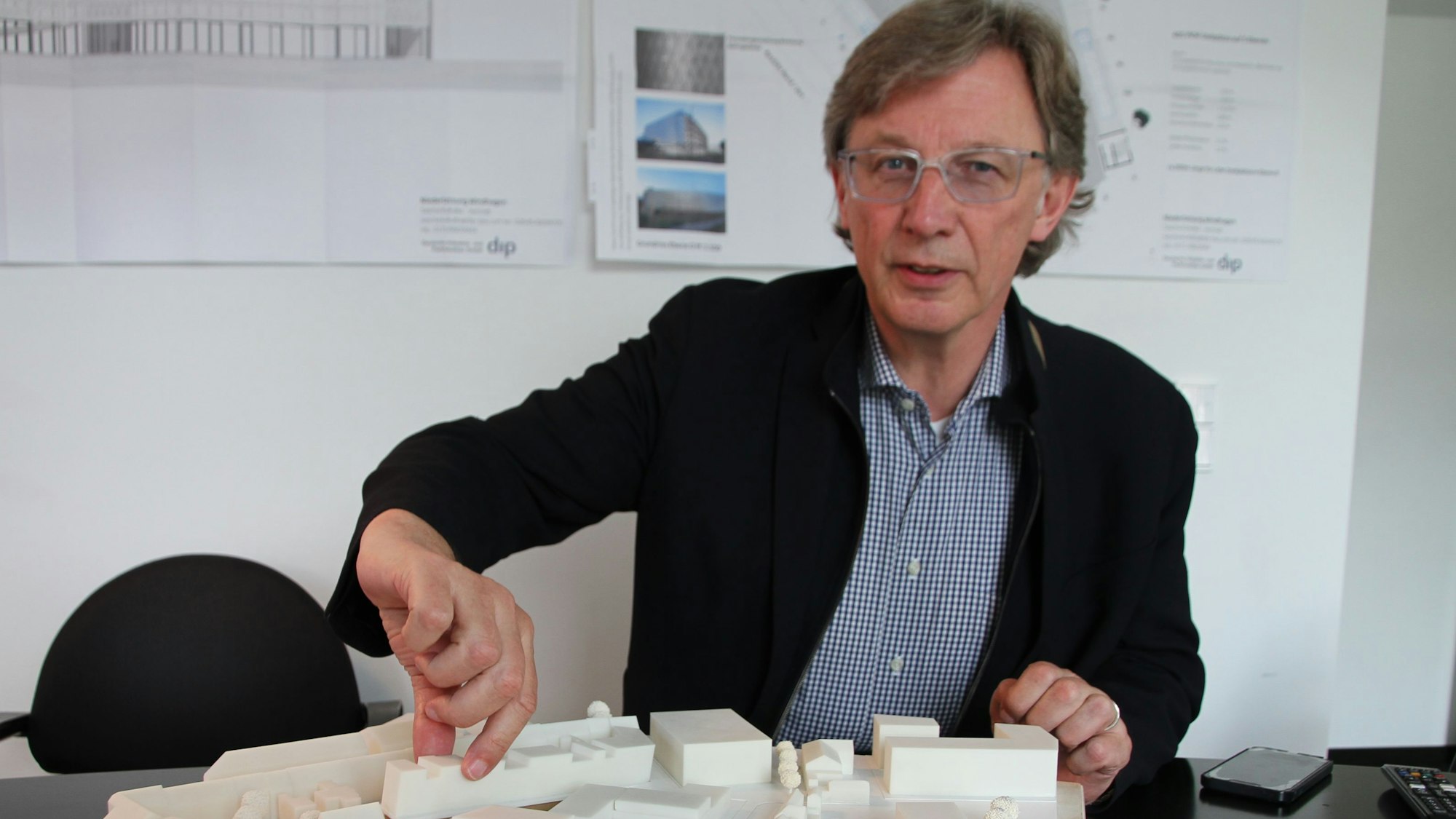 André Kuchheuser, der Vorstand der Siegburger Stadtbetriebe, sitzt in einem Büro vor einem Architektur-Modell.